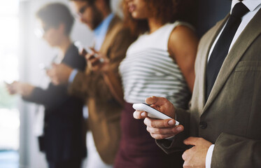 Aufkleber - Keep track of industry developments just by logging in. Shot of a businessperson using his cellphone with colleagues blurred in the background.