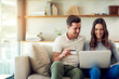 © Jadon B/peopleimages.com - Lets treat ourselves. Weve earned it. Shot of a happy young couple making a credit card payment on a laptop together at home.