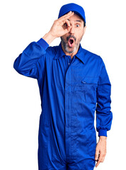 Sticker - Middle age handsome man wearing mechanic uniform doing ok gesture shocked with surprised face, eye looking through fingers. unbelieving expression.