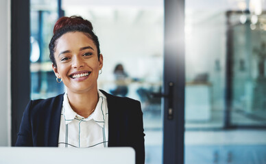 Wall Mural - Reaching my goals one workday at a time. Shot of a young businesswoman using a laptop in a modern office.