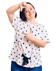 Sticker - Brunette woman with down syndrome wearing casual clothes smiling making frame with hands and fingers with happy face. creativity and photography concept.