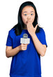 Young chinese woman holding reporter microphone covering mouth with hand, shocked and afraid for mistake. surprised expression
