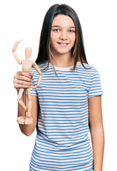 Sticker - Young brunette girl with long hair holding small wooden manikin looking positive and happy standing and smiling with a confident smile showing teeth