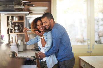 Aufkleber - Dinner made with love. Shot of a young woman giving her husband a taste of the food that shes preparing at home.