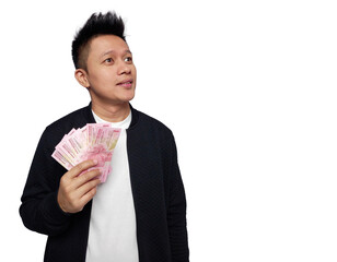 Canvas Print - Young man with hopeful facial expression looking up and holding indonesian money