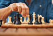 © Malik E/peopleimages.com - Play, chess and hands with a king on a board game with a strategy in tournament in home. Checkmate, chessboard and smart man or male playing in a sports contest or problem solving challenge for mind.