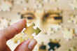 Hand holding one puzzle on jigsaw Puzzle Of Female Face from ancient painting on wooden background