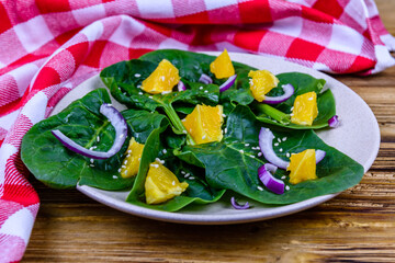 Wall Mural - Salad with spinach leaves, pieces of orange, sesame seeds and onion in a ceramic plate