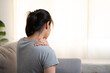 Tired woman touch stiff neck feeling hurt joint back pain rubbing massaging tensed muscles suffer from shoulder ache after long computer work study in incorrect posture sit on sofa at home