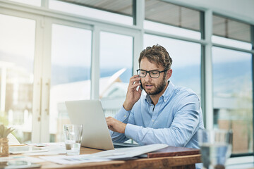 Aufkleber - Passion drives his performance. Shot of a young businessman using a phone and laptop at his desk in a modern office.