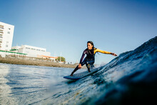 A Surfer Girl Rides Her Longboard During A Before Sunset Session