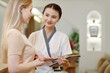 © DragonImages - Spa salon administrator asking client to fill form on tablet computer