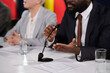 © pressmaster - Close-up of young African American delegate sitting in front of microphone and making speech to audience at conference