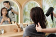 © DragonImages - Hairdresser blow drying hair of female client