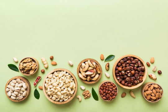 mixed nuts in wooden bowl. mix of various nuts on colored background. pistachios, cashews, walnuts, 