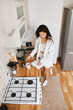 © olga pink - Portrait long hair brunette Asian woman in white clothes making morning hot cup coffee in kitchen