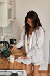 © olga pink - Young happy brunette woman making hot tasty beverage coffee, sweet breakfast, reading book