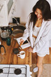 © olga pink - Portrait long hair brunette Asian woman in white clothes making morning hot cup coffee in kitchen
