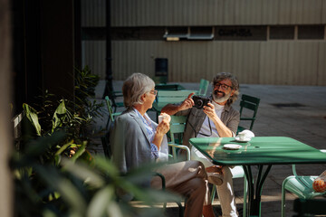 Wall Mural - Senior couple taking pictures in cafe.