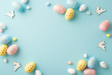 Wall Mural - Easter decorations concept. Top view photo of colorful easter eggs and bunnies on isolated pastel blue background with copyspace in the middle