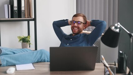 Wall Mural - Watching and smiling. Male freelancer is sitting by table with laptop is having fun.