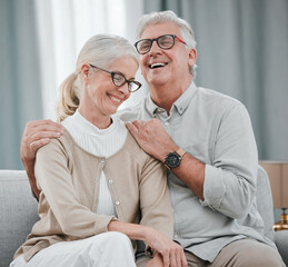 Wall Mural - Laughing, love or funny old couple hugging on house living room sofa together enjoying quality time. Smile, peace or happy mature man bonding with a supportive senior woman in retirement at home