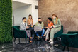 © Mediteraneo - Businesspeople working in an office lobby. Group of  businesspeople sitting together in a co-working space