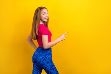 Canvas Print - Photo of teenager girl wearing pink crop top blue trousers point finger empty space advertise new shop brand isolated on yellow color background