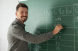© New Africa - Happy teacher explaining English at blackboard in classroom