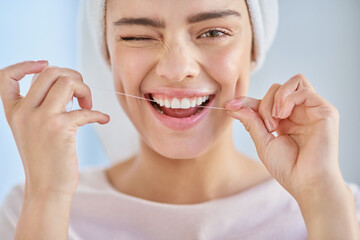 Wall Mural - Dont forget to floss. Cropped portrait of a beautiful young woman flossing her teeth in the bathroom at home.