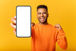 © Vadim Pastuh - Young indian man demonstrates smartphone with blank screen and rejoicing, guy likes mobile app, looking and smiling at the camera, feels satisfied, isolated