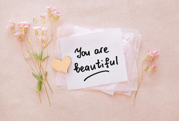 You are beautiful - card with motivational and encouraging lettering with flowers and heart on pink background