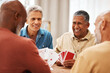 © Malik E/peopleimages.com - Senior man, friends and laughing for card games on wooden table in fun activity, social bonding or gathering. Group of happy elderly men with cards for poker game enjoying play time together at home