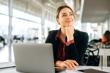positive caucasian businesswoman, office employee, product manager, sits in a business center, worki
