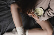 Woman sitting on the bed hold pint of pistachio ice-cream and spoon. No face. Eating in bed. Happy beautiful woman resting in her comfortable bed at home. Yummy.