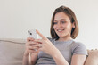 © ADDICTIVE STOCK - Content woman messaging via smartphone while sitting on sofa
