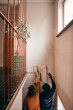 © Maskot - Rear view of couple taking measurement while hanging painting on wall at home