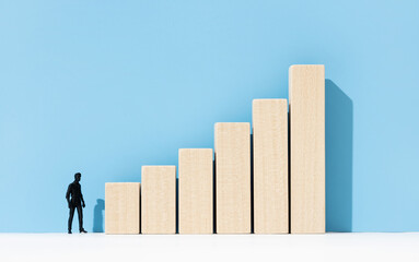 Wall Mural - Human figurine looking at a growing bar chart. Career development concept. Copy space