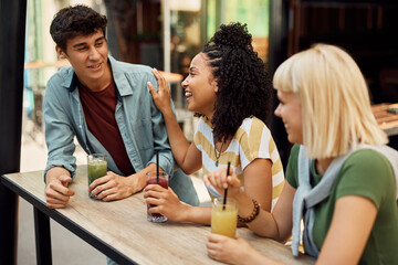 Wall Mural - Young black woman laughs while talking to her friends in cafe.