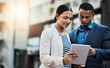 © Donson/peopleimages.com - Business moves along as they do. Shot of two businesspeople using a digital tablet in the city.