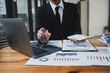 © SOMKID - Businessman hands working on laptop computer with market report document and management business project, Business accounting concept.