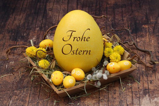grußkarte frohe ostern: osternest mit gelben ostereiern und einem beschrifteten osterei.