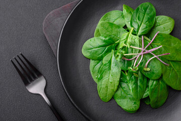 Fresh green spinach leaves on a black ceramic plate