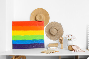 Poster - Painting of LGBT flag, wooden hand and books on table near light wall in room