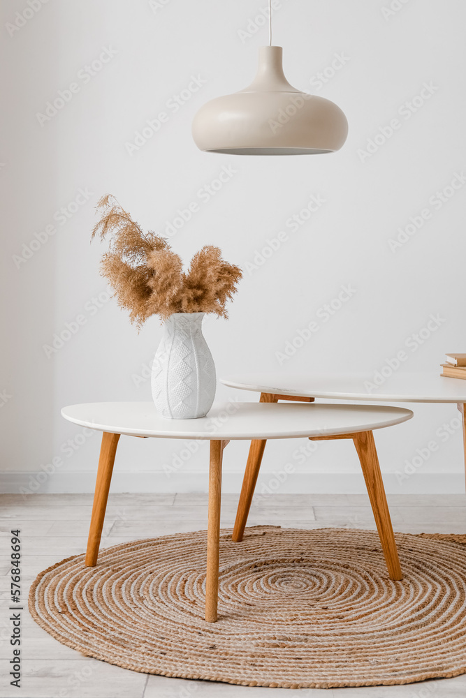 Vase with pampas grass on table near light wall in room
