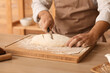 Male baker preparing dough for bread at table in kitchen, closeup