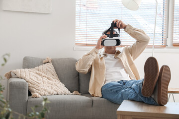 Poster - Mature man in VR glasses sitting on sofa at home