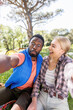 © Wavebreak Media - Vertical of happy, diverse couple having fun taking selfie in countryside, copy space
