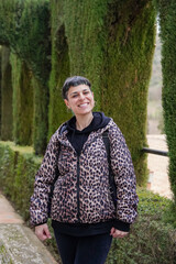 Wall Mural - portrait of lgbt non binary person in leopard coat looking at camera in a botanical garden in Granada. Gay Pride's day