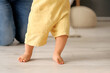 © Pixel-Shot - Baby boy learning to walk with his mother in bedroom, closeup